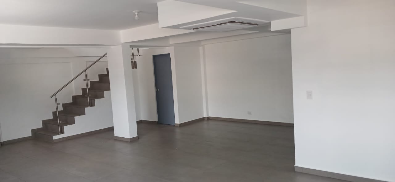 Espacio diáfano terminado con escalera y acabados en gris y blanco